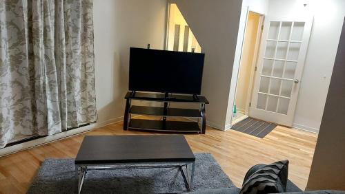 a living room with a flat screen tv on a stand at Spacious and comfortable accommodation in Longueuil