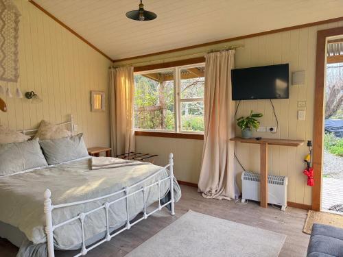 a bedroom with a bed and a tv and a window at Wisteria Way in Opononi