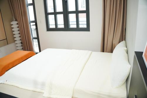 a white bed in a room with a window at Be Staycation Sai Gon in Ho Chi Minh City