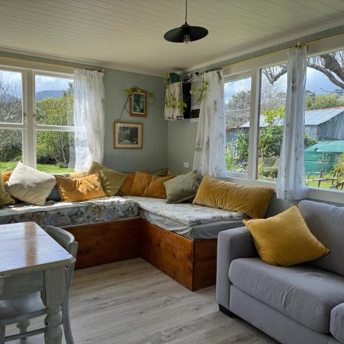 a living room with a couch and windows at Wisteria Way in Opononi