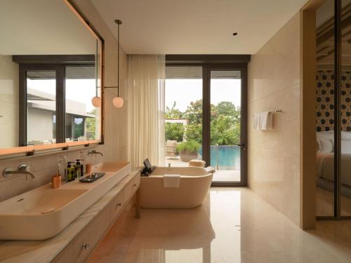 a bathroom with a tub and a sink and a mirror at Raffles Sentosa Singapore in Singapore