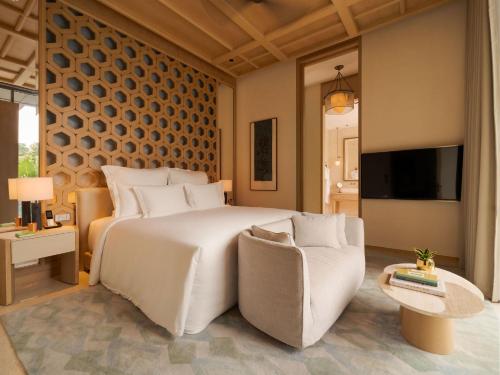 a bedroom with a large white bed and a chair at Raffles Sentosa Singapore in Singapore