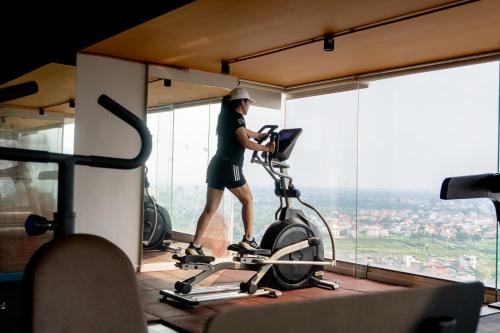 a woman running on a bike in a gym at Mandala Hotel & Suites Hải Dương in Bảo Thap