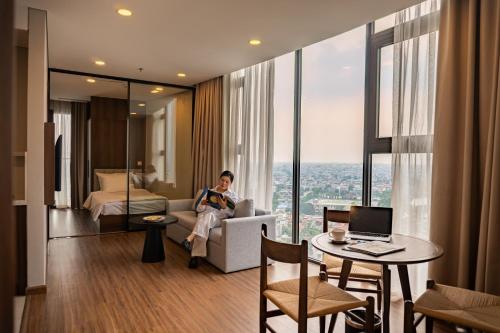 a woman sitting on a couch in a hotel room at Mandala Hotel & Suites Hải Dương in Bảo Thap
