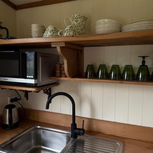 a kitchen with a sink and a microwave at Wisteria Way in Opononi