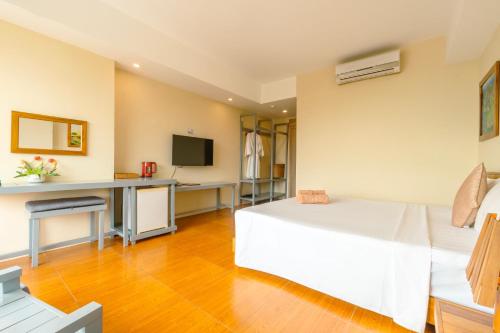 a bedroom with a bed and a desk with a television at Golden Daisy Hotel Phu Quoc in Phu Quoc