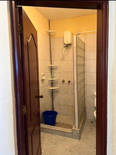 a bathroom with a shower with a blue bucket at Sunrise Apartments in Nyali