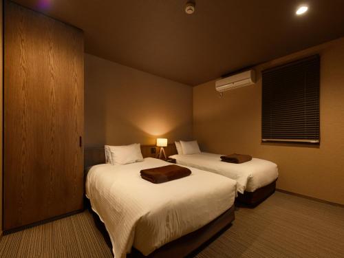 a hotel room with two beds and a window at the villa NOKI in Wada