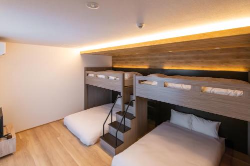 two bunk beds in a room with wooden floors at ReLA 柏駅北 in Kashiwa