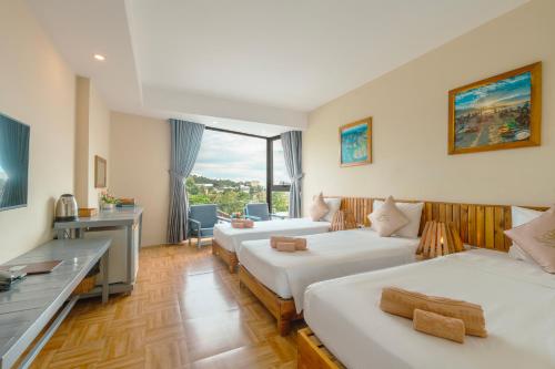 a hotel room with two beds and a desk at Golden Daisy Hotel Phu Quoc in Phu Quoc