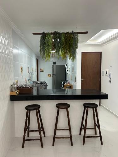 コンデにあるApartamento 100m da praiaのキッチン(黒いカウンター、バースツール2つ付)