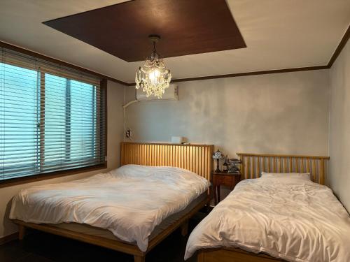 two beds in a bedroom with a chandelier at Hongdae Main Street Unique Interior, Spacious Room in Seoul