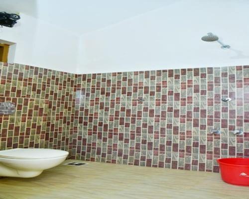 a bathroom with a toilet and a tiled wall at Bamboo world kuruva in Pulpally