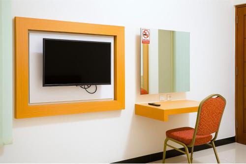 a room with a tv and a chair and a desk at Djuragan Kamar Dmangkoe in Bonorejo