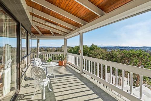 a porch with white chairs and a table on it at Spacious 4BR Retreat With Stunning Brisbane View in Rochedale South