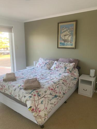 a bed with a comforter and pillows in a bedroom at Noble House in Tathra