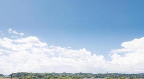 a blue sky with clouds and trees in a field at Hotel SP Haruno in Kochi