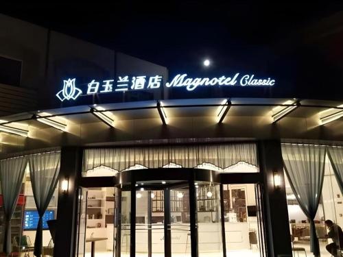 a building with a sign on the front of it at Magnotel Business Jining Huancheng North Road in Jining