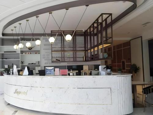 a lobby with a reception counter and lights at Magnotel Business Jining Huancheng North Road in Jining