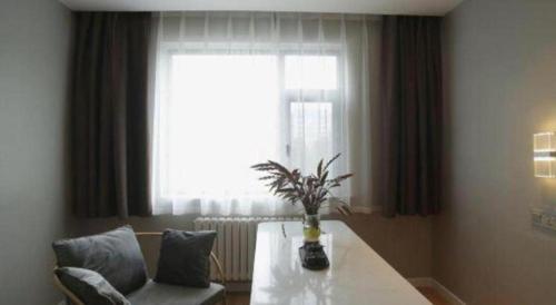 a living room with a table and a window at Magnotel Business Jining Huancheng North Road in Jining