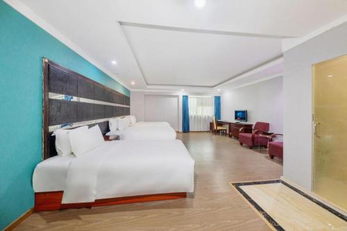 a hotel room with a large white bed and a desk at Kui Chong Holiday Hotel in Shenzhen