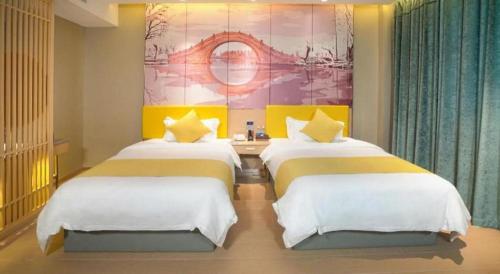 two beds in a room with a painting on the wall at Quanzhou Binhai Hotel in Quanzhou