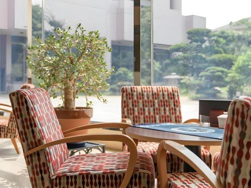 a table and chairs in a room with a potted plant at Hotel Royal Hill Fukuchiyama and Spa in Fukuchiyama