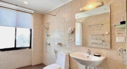 a bathroom with a sink and a toilet and a mirror at Khang Residency Thimphu in Thimphu
