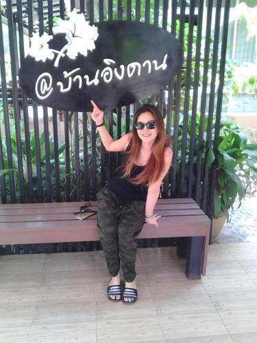 a woman sitting on a bench with a sign at Baan Ing Daan in Amnat Charoen