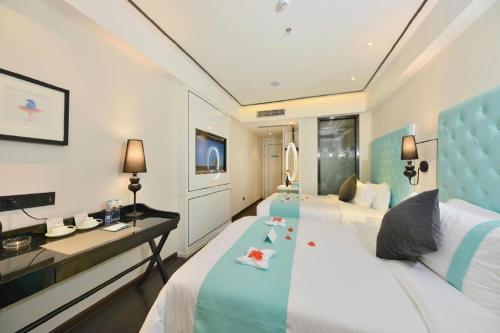 ein Hotelzimmer mit zwei Betten und einem Schreibtisch in der Unterkunft Xana Hotelle Guangzhou Tiyuxi Road Metro Station Branch in Guangzhou
