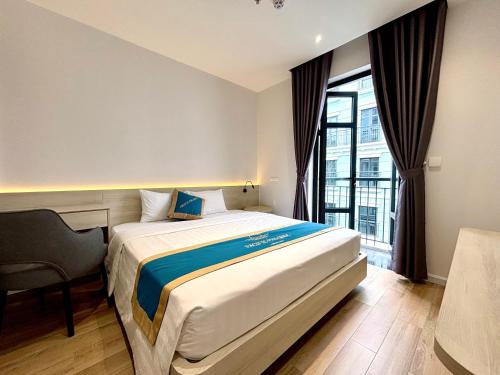 a bedroom with a bed and a chair and a window at Pacific Apartment & Hotel Phu Quoc in Phu Quoc