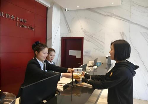 two women are shaking hands in an office at City Comfort Inn Yingcheng Railway Station Shanghe Square in Xiaogan