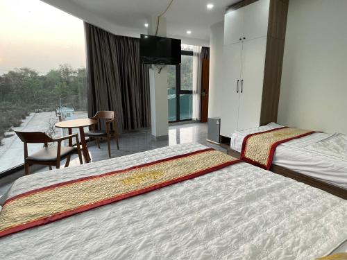 a hotel room with two beds and a table at Snu Motel - Cao Bằng in Cao Bằng