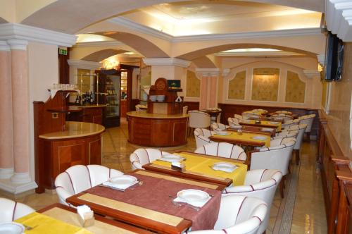 a restaurant with wooden tables and white chairs at Hotel Il Principe in Milazzo