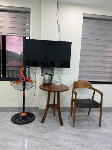 a room with a table and a chair and a television at Snu Motel - Cao Bằng in Cao Bằng