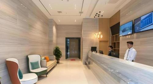 a lobby with two people standing at a counter at City Comfort Inn Wuhan International Expo Center Yongwang in Wuhan