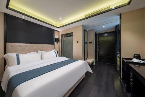 a bedroom with a large white bed and a desk at Xana Hotelle Wuxi Railway Station Zhongshan Road in Wuxi