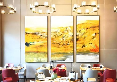 a dining room with three paintings on the wall at E-Cheng Hotel Liuzhou Sanjiang Fengyu Bridge in Sanjiang