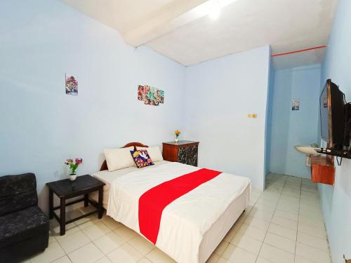 a bedroom with a bed and a chair and a television at YUTAKA INN Araya Malang in Blimbing