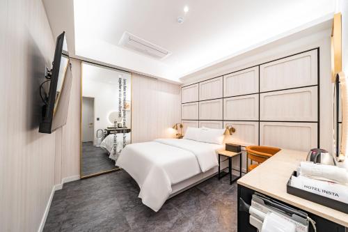 Un dormitorio con una cama blanca y un espejo. en HotelInsta Main Branch, en Pŏlt'ŏ