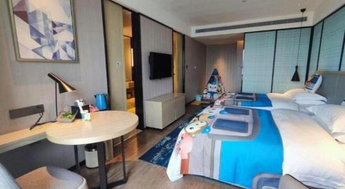 a bedroom with a large bed with a desk and a table at Echarm Hotel Nanning the MixC Dongmeng Business District in Nanning