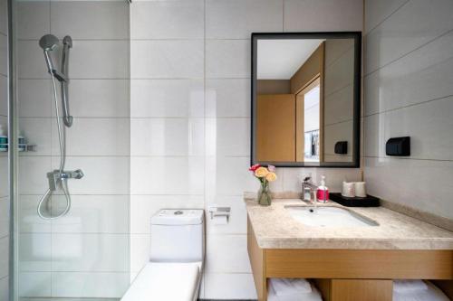 a bathroom with a sink and a shower with a mirror at City Comfort Inn Shaoguan Biguiyuan Phoenix City Gold Village in Shaoguan