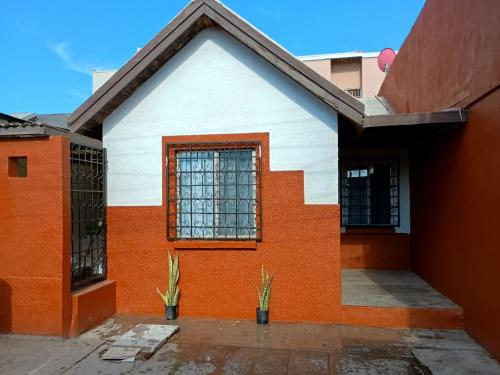 an orange and white house with a window at Casa a una cuadra de la playa in Ensenada