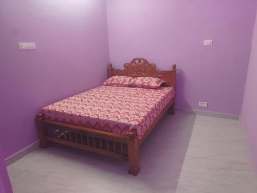 Cama pequeña en habitación con paredes moradas en Uthresh Guest House, en Tiruvannāmalai