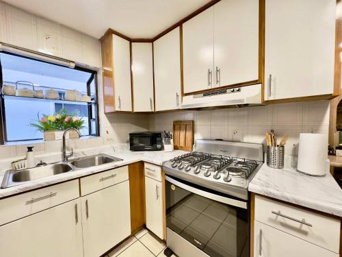 a kitchen with white cabinets and a stove and a sink at Casa Lomas Cozy 3 Bedroom 2 Bath House by Xolos Stadium in Tijuana