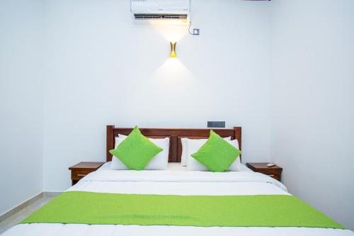 a bedroom with a bed with green and white pillows at Hikka Shells in Hikkaduwa