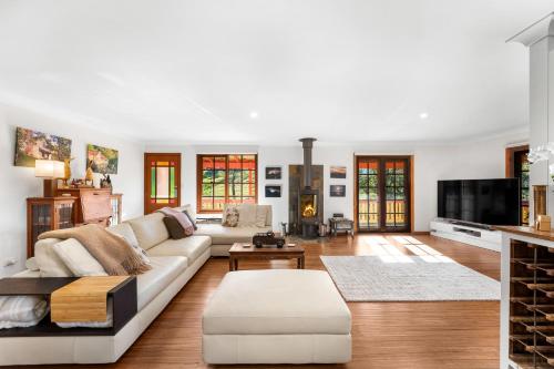 a living room with a couch and a tv at Picturesque Pet-Friendly Farm Stay, Central Tilba , Near Mystery Bay! in Central Tilba