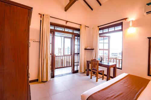 a bedroom with a bed and a desk with a balcony at Amara White Villa in Ahungalla
