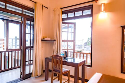 a room with a table and a balcony with windows at Amara White Villa in Ahungalla