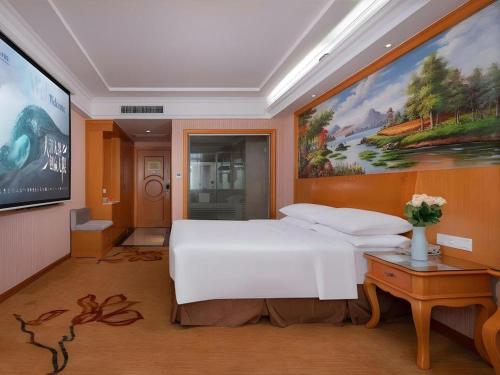 a bedroom with a large white bed and a painting at Vienna Hotel Guangdong Shantou South Bus Station in Shantou
